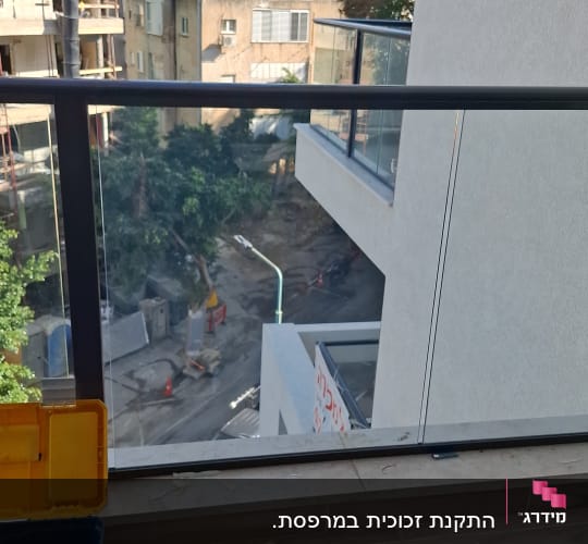 התקנת מעקה זכוכית במרפסת לצד כלי עבודה של מתקין